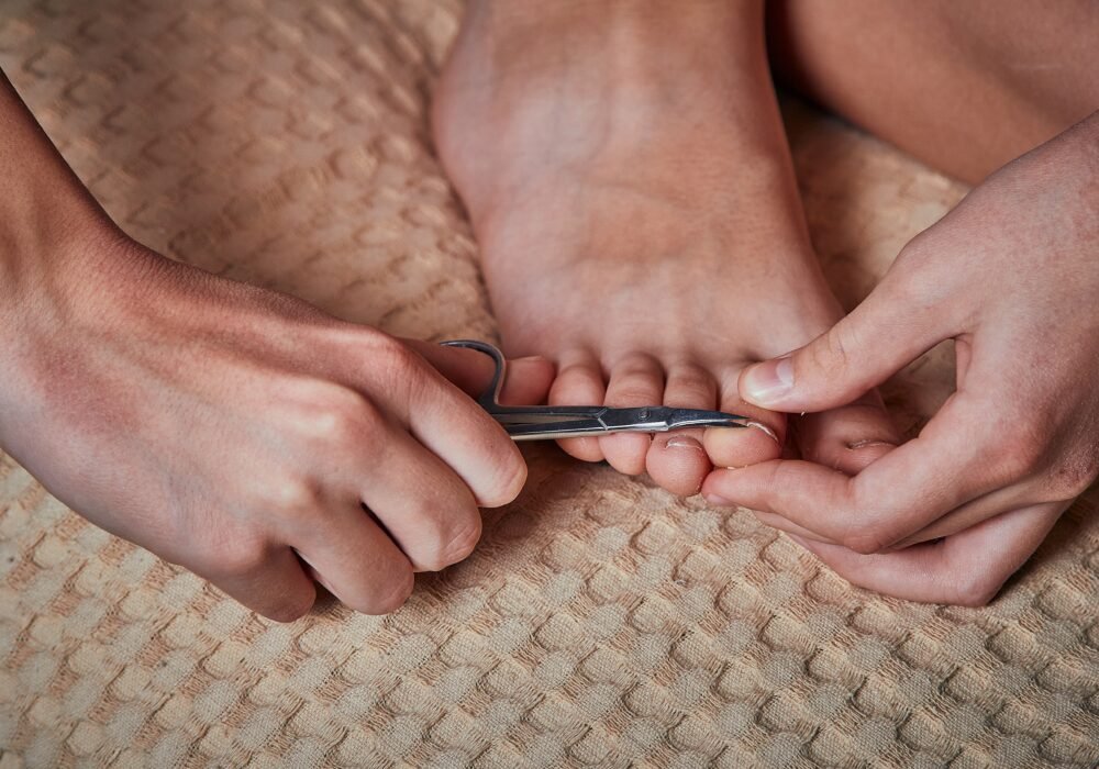 Close-up of hands trimming a toenail straight across