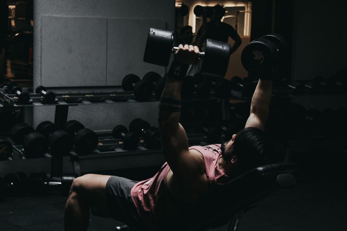 man performing a dumbbell bench press on a weight bench