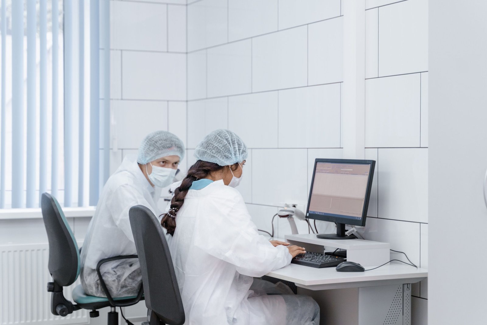Two researchers reviewing clinical trial data on a computer in a lab
