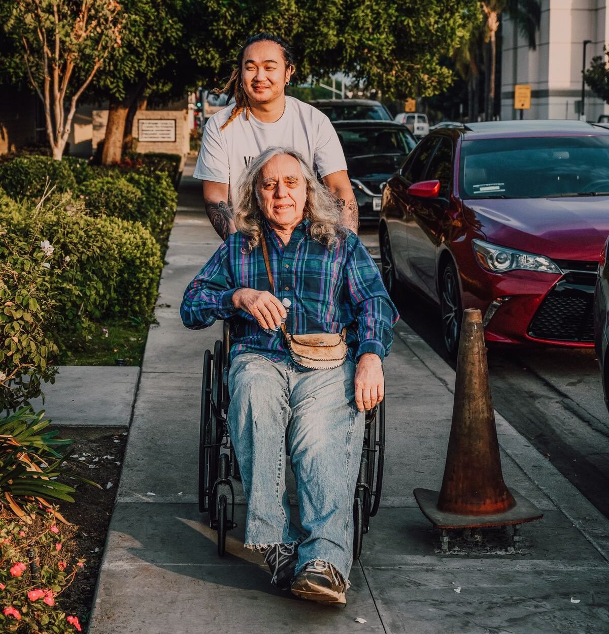 caregiver pushing an adult in a manual wheelchair outdoors