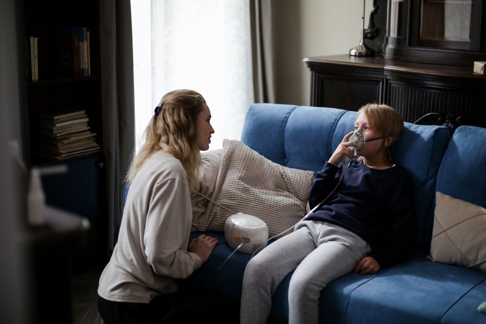 mother helping her child use a nebulizer at home