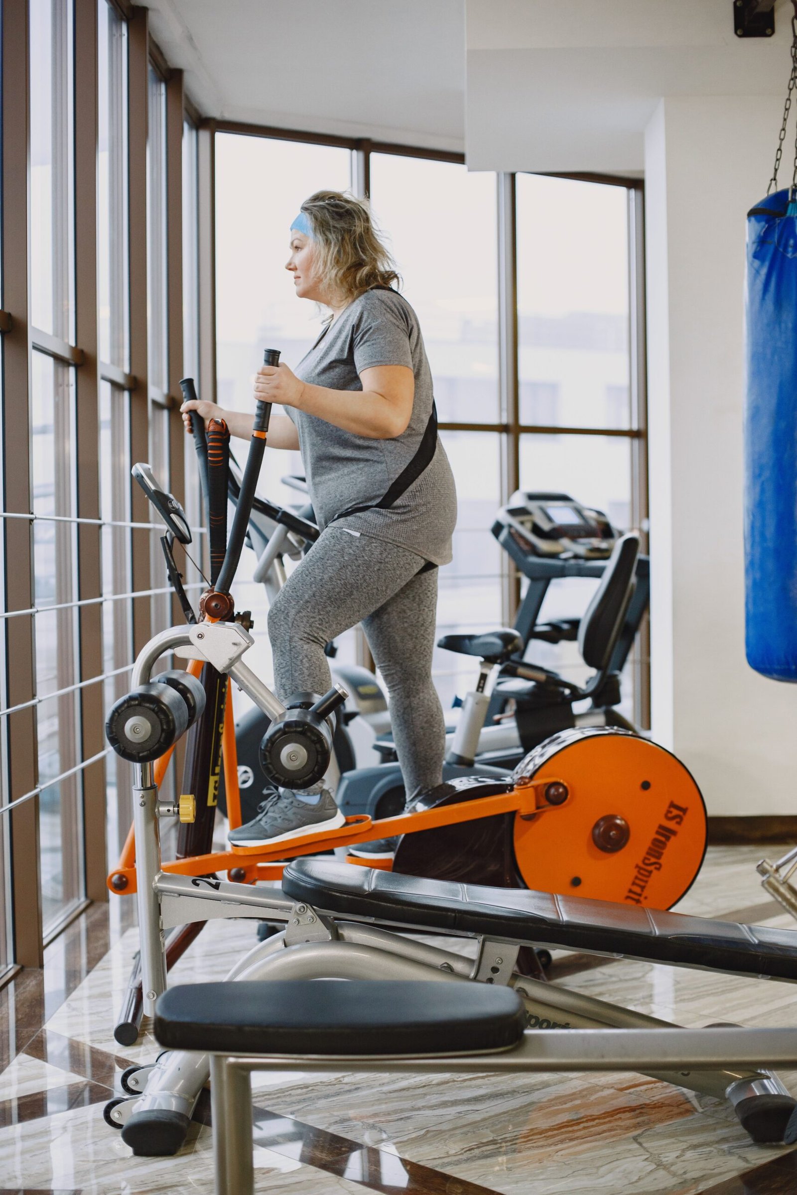 Intensity has a bigger impact on elliptical calorie burn than almost any other factor woman exercising on an elliptical trainer in a bright modern gym