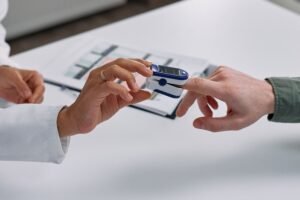 doctor placing a pulse oximeter on a patient fingertip to read oxygen saturation