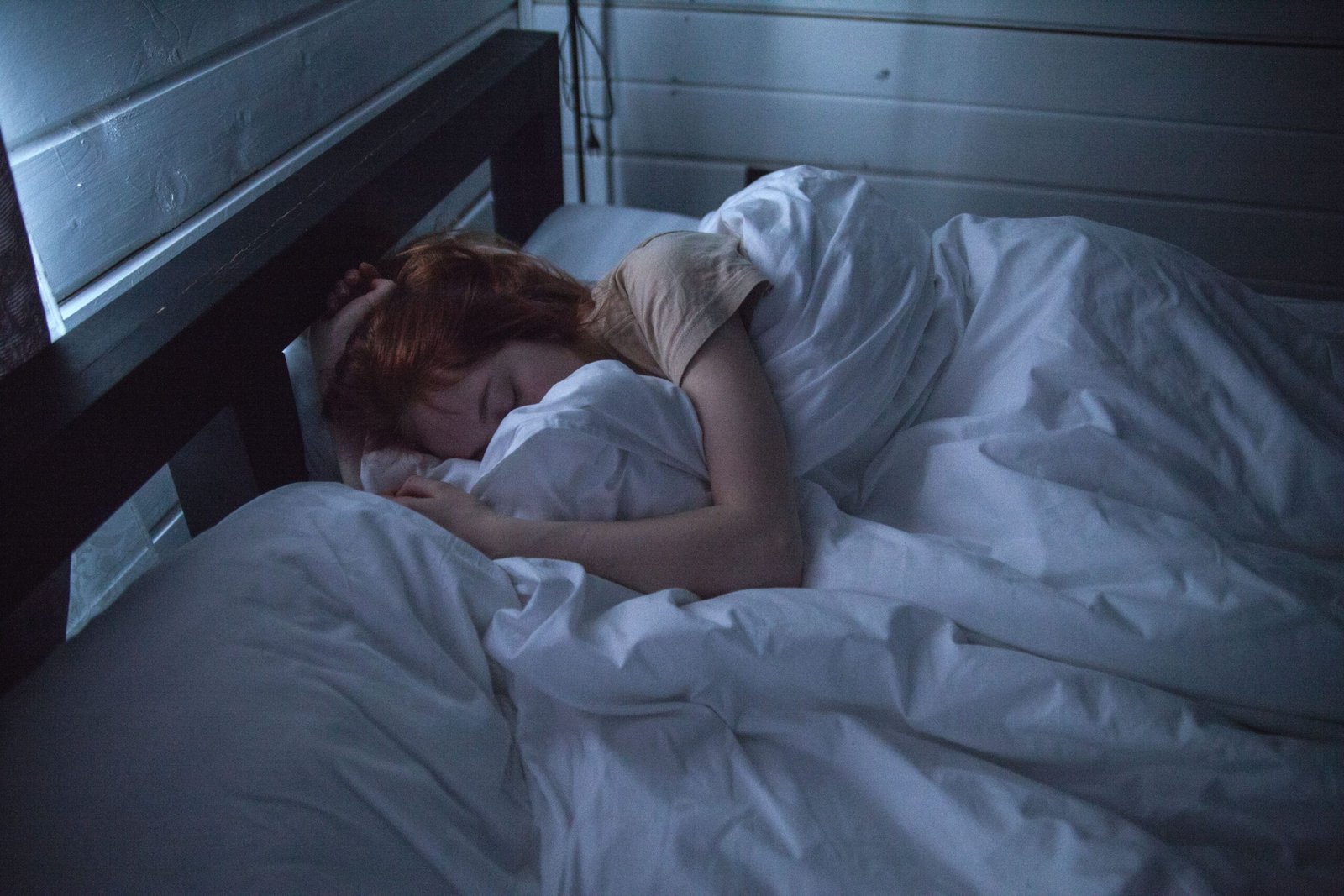 Woman sleeping on her back with a supportive pillow while wearing a neck brace