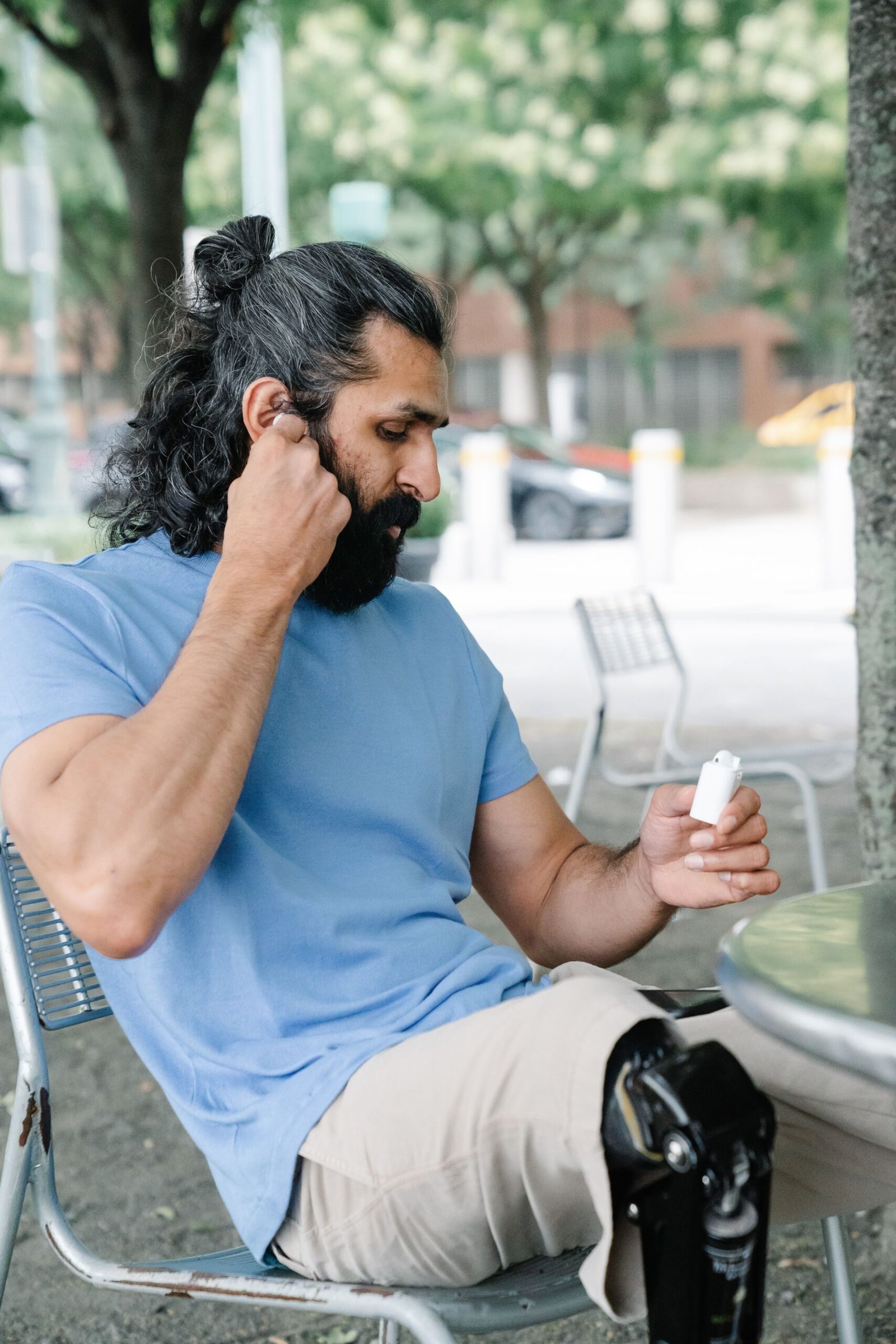 Man adjusting his hearing aid outdoors man adjusting his hearing aid outdoors