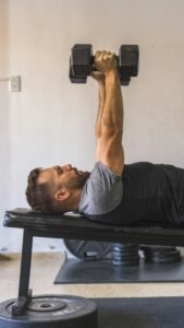 Man performing a dumbbell bench press on a flat weight bench