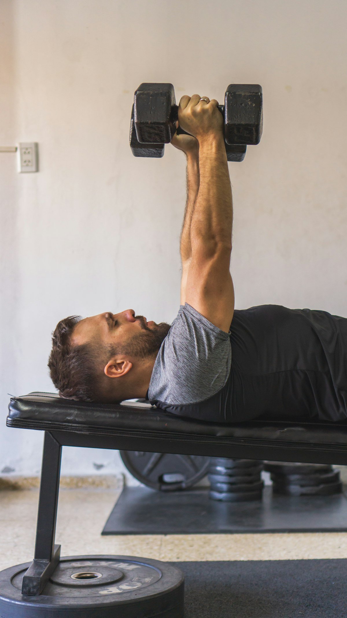 Man performing a dumbbell bench press on a flat weight bench