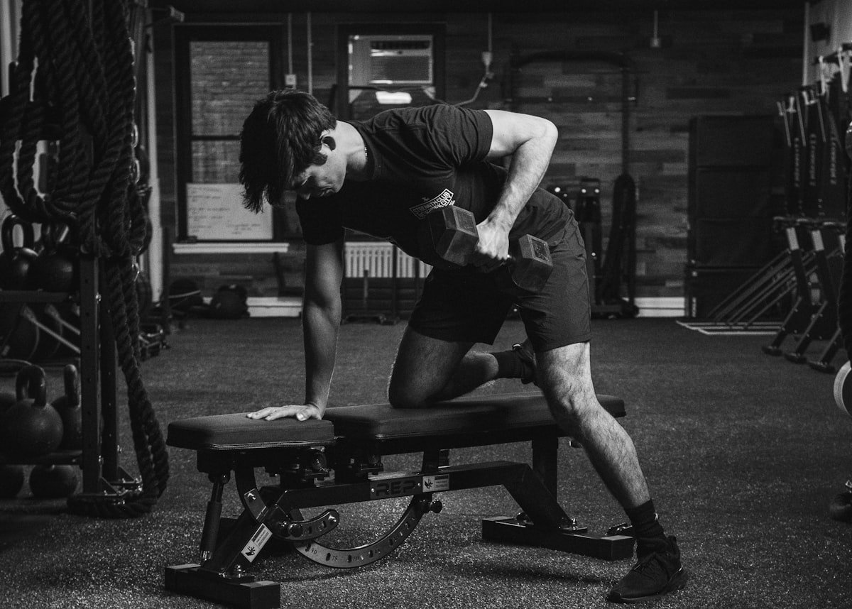 Man using an adjustable weight bench with a dumbbell in a home gym