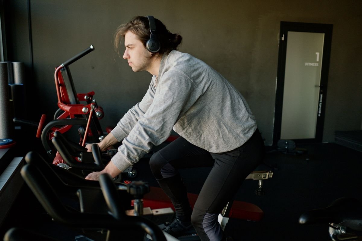 Man in athletic wear pedaling on a stationary cycling machine indoors