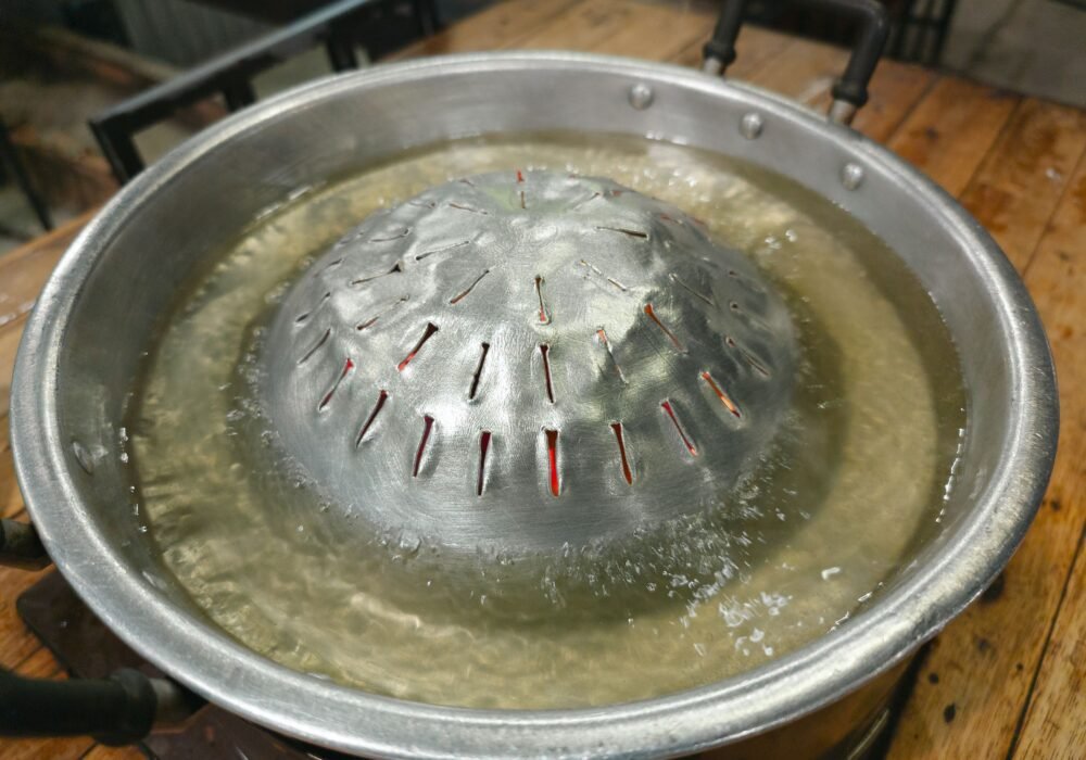 Pot of water boiling with steam rising, illustrating the first stage of distillation