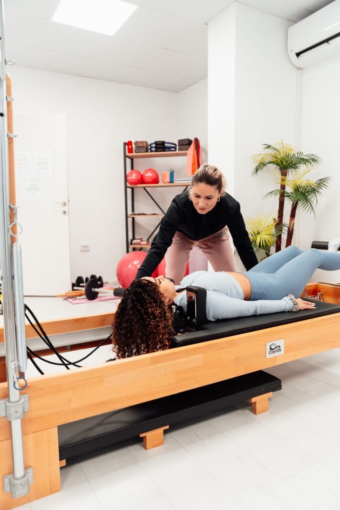 Instructor and student working together on a Pilates reformer