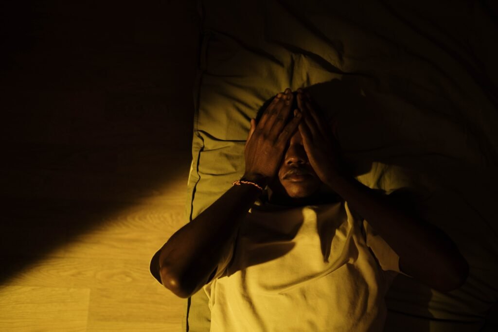 man lying in bed in a dark room
