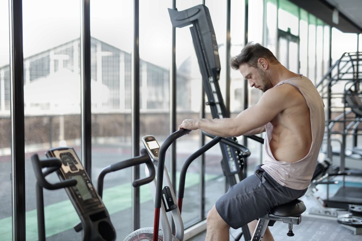 Muscular man training on a stationary cycling machine in a fitness center