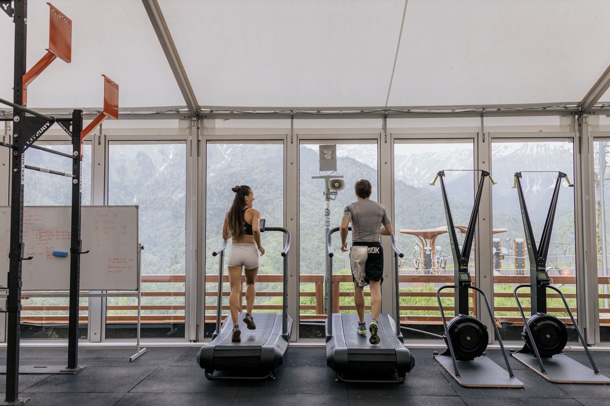 Two people running side by side on treadmills in a modern gym